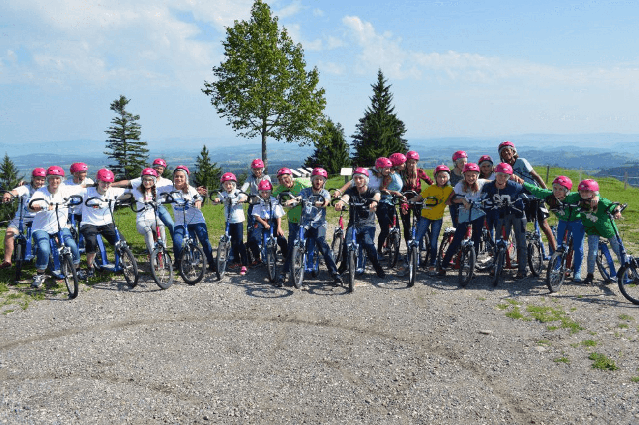 gruppenfoto der teilnehmer eines sommercamps auf einem berg mit trotinets